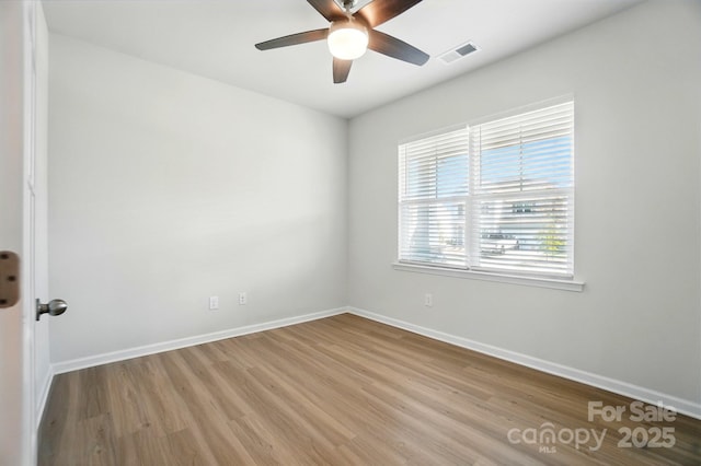 spare room with wood finished floors, baseboards, a ceiling fan, and visible vents