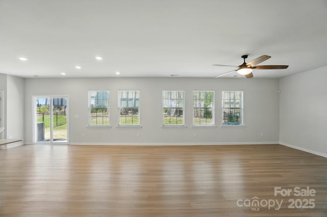 unfurnished living room with wood finished floors, a ceiling fan, plenty of natural light, and recessed lighting