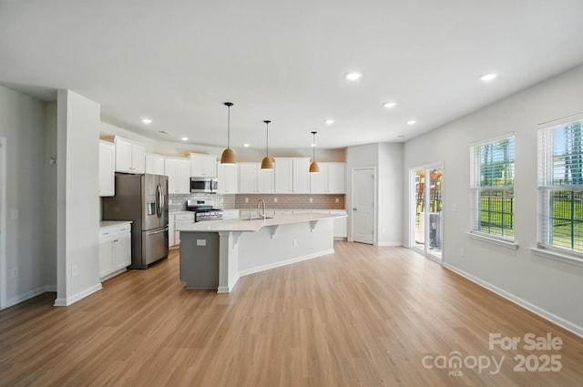 kitchen featuring light countertops, light wood-type flooring, a kitchen bar, stainless steel appliances, and decorative backsplash