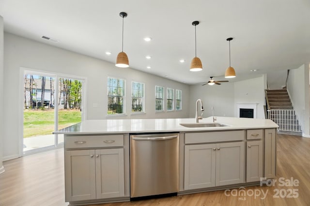 kitchen with light wood-type flooring, a ceiling fan, visible vents, dishwasher, and a sink