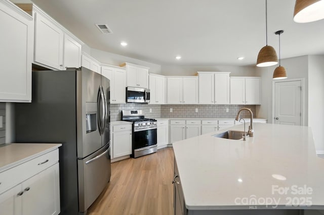 kitchen featuring tasteful backsplash, light countertops, visible vents, appliances with stainless steel finishes, and a sink