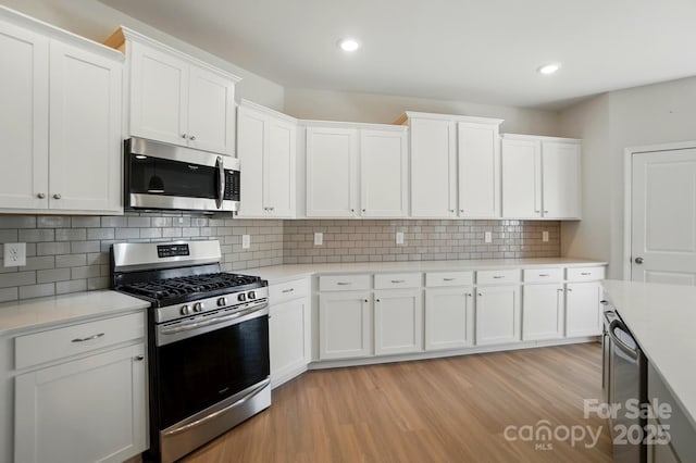 kitchen with light wood finished floors, light countertops, white cabinetry, and stainless steel appliances