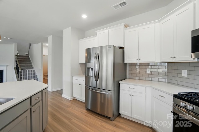 kitchen with tasteful backsplash, visible vents, light countertops, appliances with stainless steel finishes, and light wood-style floors