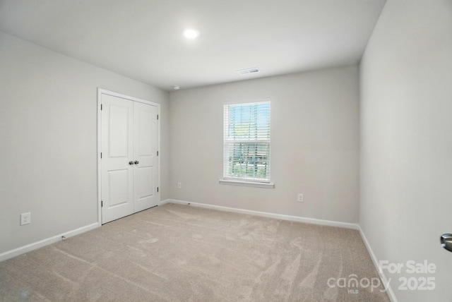 unfurnished room featuring carpet, visible vents, and baseboards
