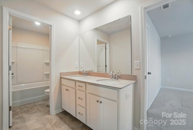 bathroom featuring toilet, double vanity, a sink, and visible vents