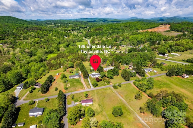 drone / aerial view featuring a wooded view and a mountain view