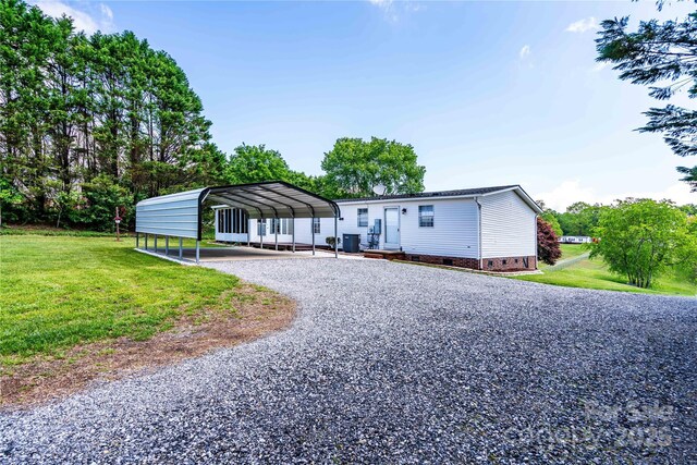 manufactured / mobile home with driveway, a detached carport, a front yard, crawl space, and central AC