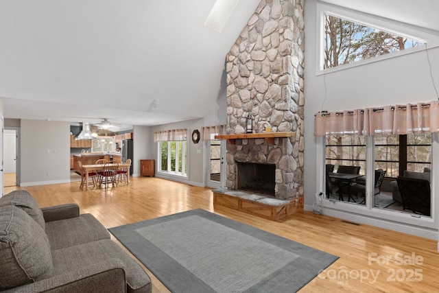 living room with a fireplace, a ceiling fan, visible vents, high vaulted ceiling, and wood finished floors