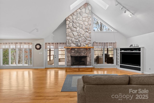 3670 Maple Creek Rd, Rutherfordton, NC 28139 - living room with rail lighting, a stone fireplace, wood finished floors, baseboards, and high vaulted ceiling