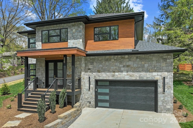 contemporary home featuring stone siding, a shingled roof, driveway, and covered porch