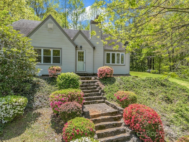 view of front of home with a chimney and roof with shingles