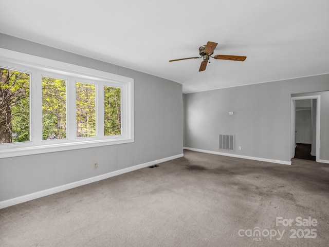 carpeted empty room featuring baseboards, a ceiling fan, and visible vents