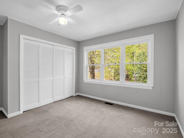unfurnished bedroom with a closet, visible vents, carpet flooring, and baseboards