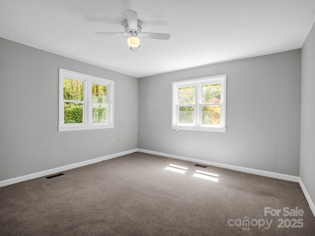 carpeted spare room featuring baseboards, a ceiling fan, and visible vents