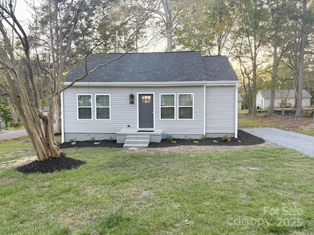 view of front of property with roof with shingles and a front lawn