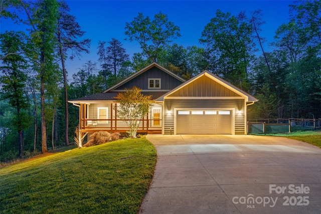 craftsman-style home with fence, an attached garage, board and batten siding, a front yard, and driveway