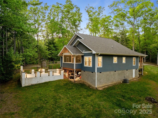 exterior space featuring a shingled roof, board and batten siding, a wooden deck, and a yard