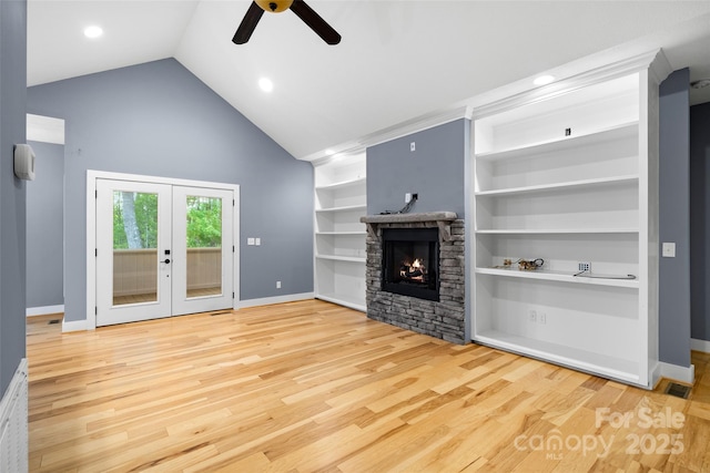 unfurnished living room with ceiling fan, a stone fireplace, wood finished floors, baseboards, and high vaulted ceiling