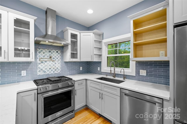 kitchen featuring open shelves, wall chimney exhaust hood, a sink, backsplash, and stainless steel appliances