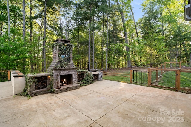 view of patio featuring fence, a gate, and an outdoor stone fireplace
