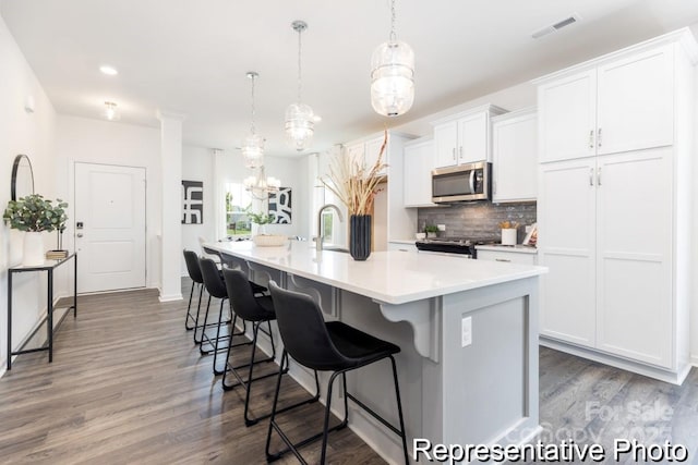 24558 Blue Heron Cir Unit 402, Lancaster, SC 29720 - kitchen featuring visible vents, stainless steel microwave, wood finished floors, a center island with sink, and backsplash