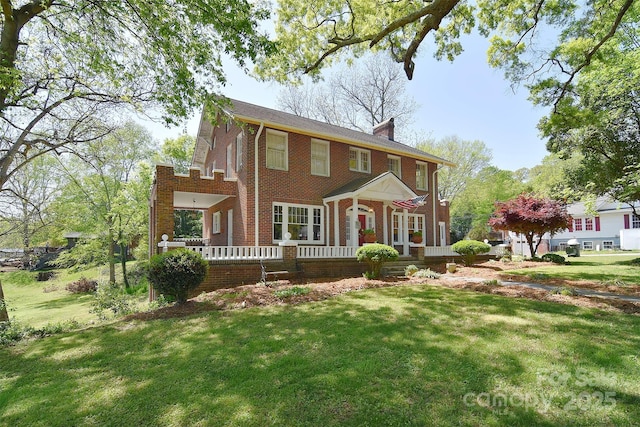 view of front facade with brick siding, a front yard, a wooden deck, and a chimney