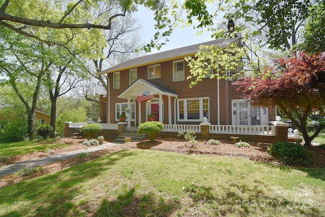 colonial-style house featuring brick siding and a front lawn