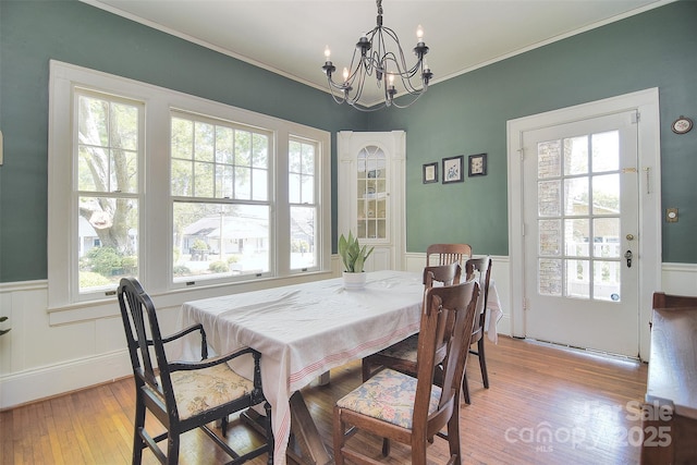 dining area with a chandelier, wood finished floors, wainscoting, and ornamental molding