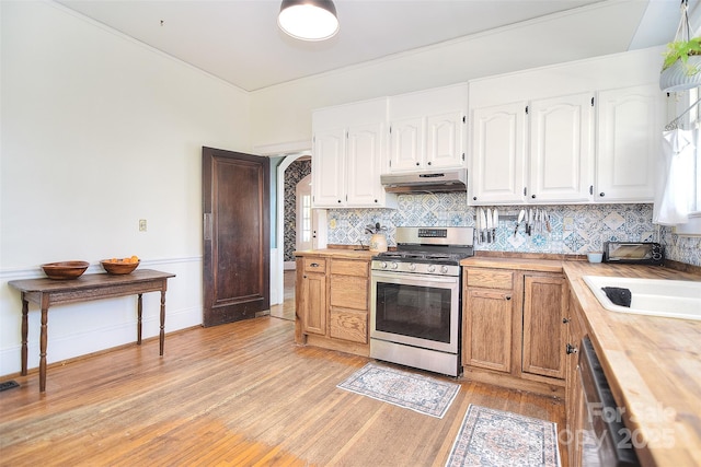 kitchen featuring appliances with stainless steel finishes, butcher block countertops, under cabinet range hood, light wood-style flooring, and a sink