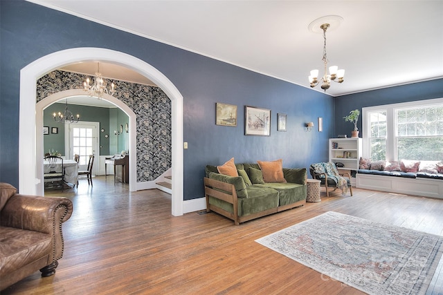 living room with a chandelier, arched walkways, wood finished floors, ornamental molding, and baseboards