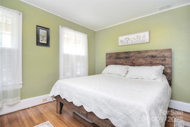 bedroom featuring baseboards, wood finished floors, and ornamental molding