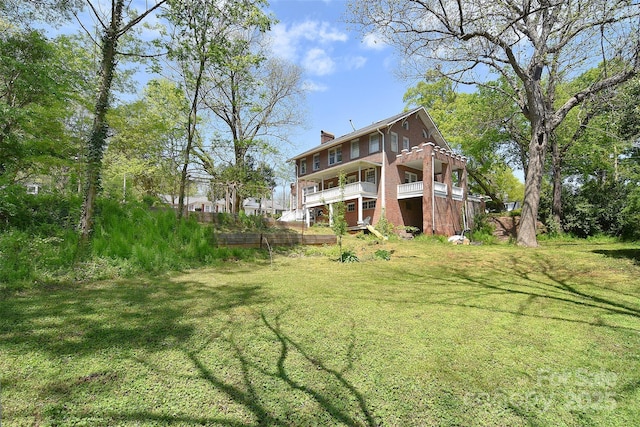 rear view of house featuring a lawn, a chimney, a deck, and brick siding