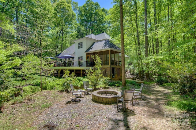 4516 Stryker Dr, Matthews, NC 28104 - rear view of house featuring a sunroom, a wooden deck, a view of trees, and an outdoor fire pit