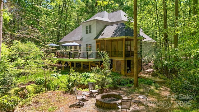 4516 Stryker Dr, Matthews, NC 28104 - back of house featuring a wooded view, a deck, a shingled roof, an outdoor fire pit, and a sunroom
