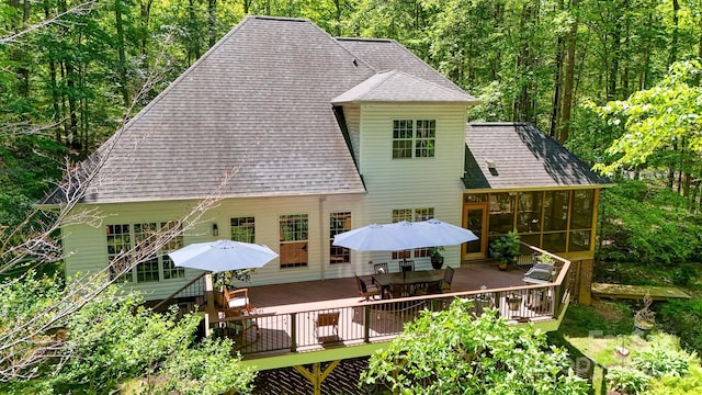 4516 Stryker Dr, Matthews, NC 28104 - rear view of property featuring a deck, outdoor dining space, roof with shingles, a view of trees, and a sunroom