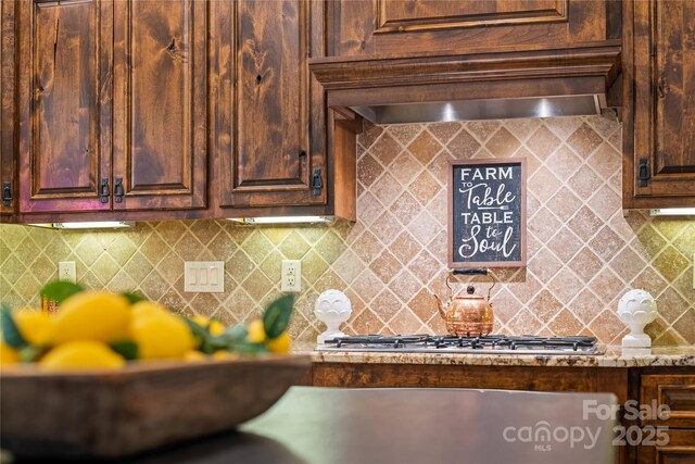 14130 Lea Point Ct, Huntersville, NC 28078 - kitchen with decorative backsplash, stainless steel gas cooktop, dark brown cabinets, and light stone countertops