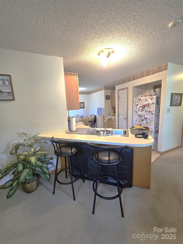 317 Robert Keever Rd, Stanley, NC 28164 - kitchen with a sink, a peninsula, a textured ceiling, a kitchen breakfast bar, and freestanding refrigerator