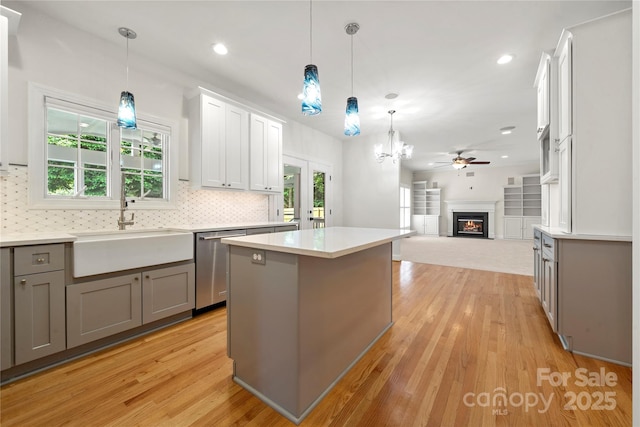 kitchen featuring a sink, light wood-type flooring, backsplash, gray cabinets, and dishwasher