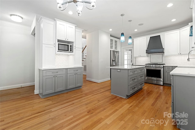 kitchen with custom exhaust hood, light wood-type flooring, baseboards, appliances with stainless steel finishes, and gray cabinetry