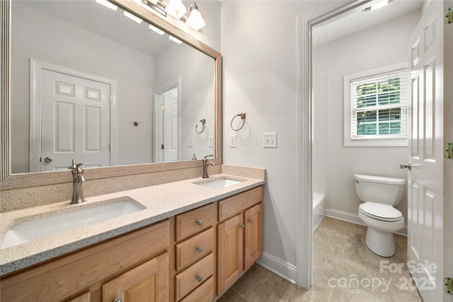 bathroom with toilet, a sink, double vanity, and baseboards