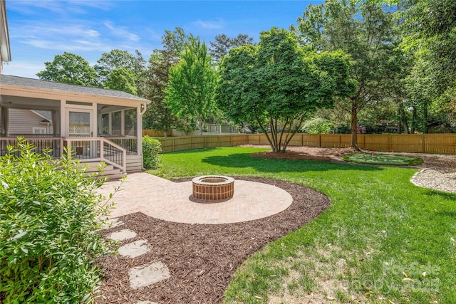 view of yard with a fenced backyard, an outdoor fire pit, a sunroom, and a patio
