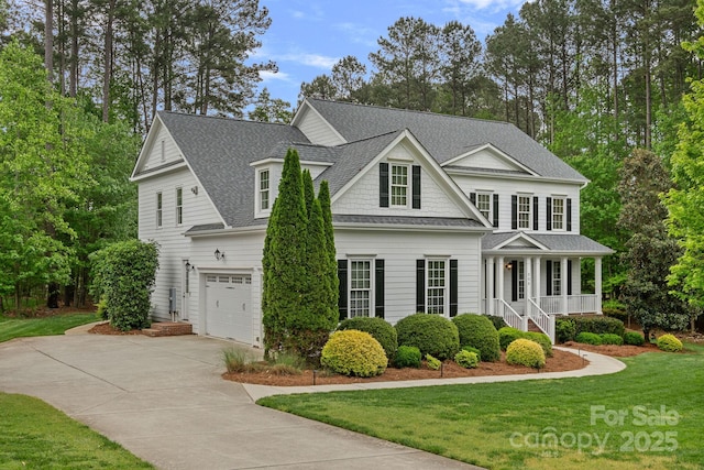 view of front of house featuring roof with shingles, driveway, a porch, a garage, and a front yard