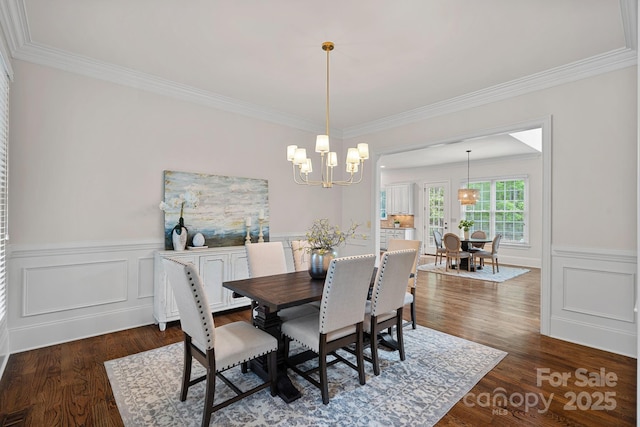 dining space with a chandelier, dark wood finished floors, ornamental molding, and wainscoting