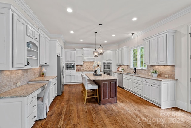 kitchen featuring a center island, tasteful backsplash, a sink, white cabinets, and appliances with stainless steel finishes