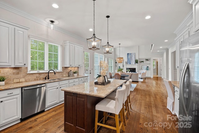 kitchen featuring a sink, open floor plan, white cabinetry, decorative backsplash, and appliances with stainless steel finishes