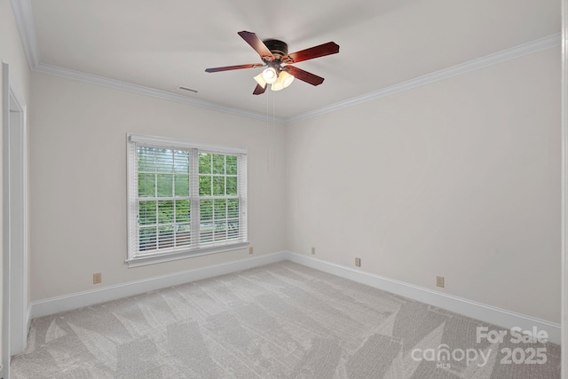 spare room with crown molding, a ceiling fan, baseboards, and light colored carpet