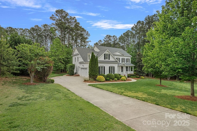view of front of home with concrete driveway, an attached garage, and a front yard