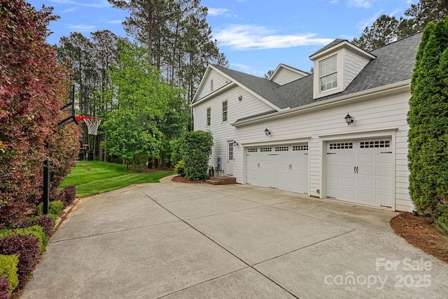 view of side of home with a lawn, driveway, roof with shingles, and a garage