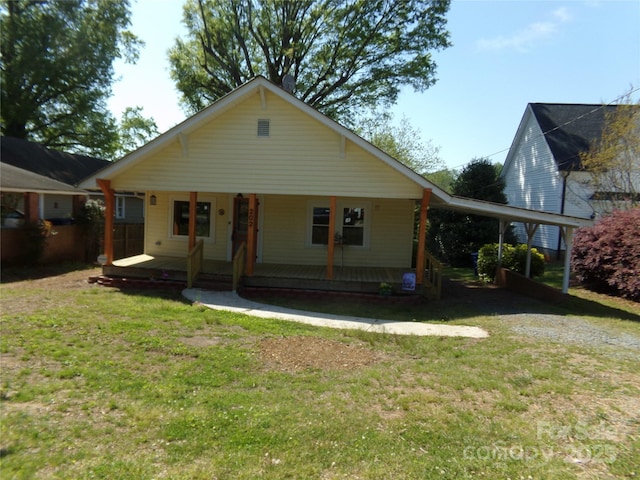 view of front of property with covered porch, an attached carport, and a front lawn