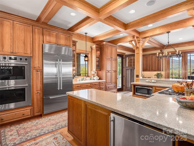 kitchen featuring beamed ceiling, brown cabinetry, appliances with stainless steel finishes, and an inviting chandelier